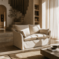 Shane Beige Linen Slipcover Loveseat w/2 Pillows 58" in a cozy living space with warm light.