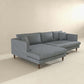 The Blake Velvet Upholstered L-Shape Chaise Sofa Sectional 107 by Ashcroft Furniture features plush velvet upholstery, wooden legs, and a reversible chaise for comfort and flexibility in a minimalist room with light walls and flooring.