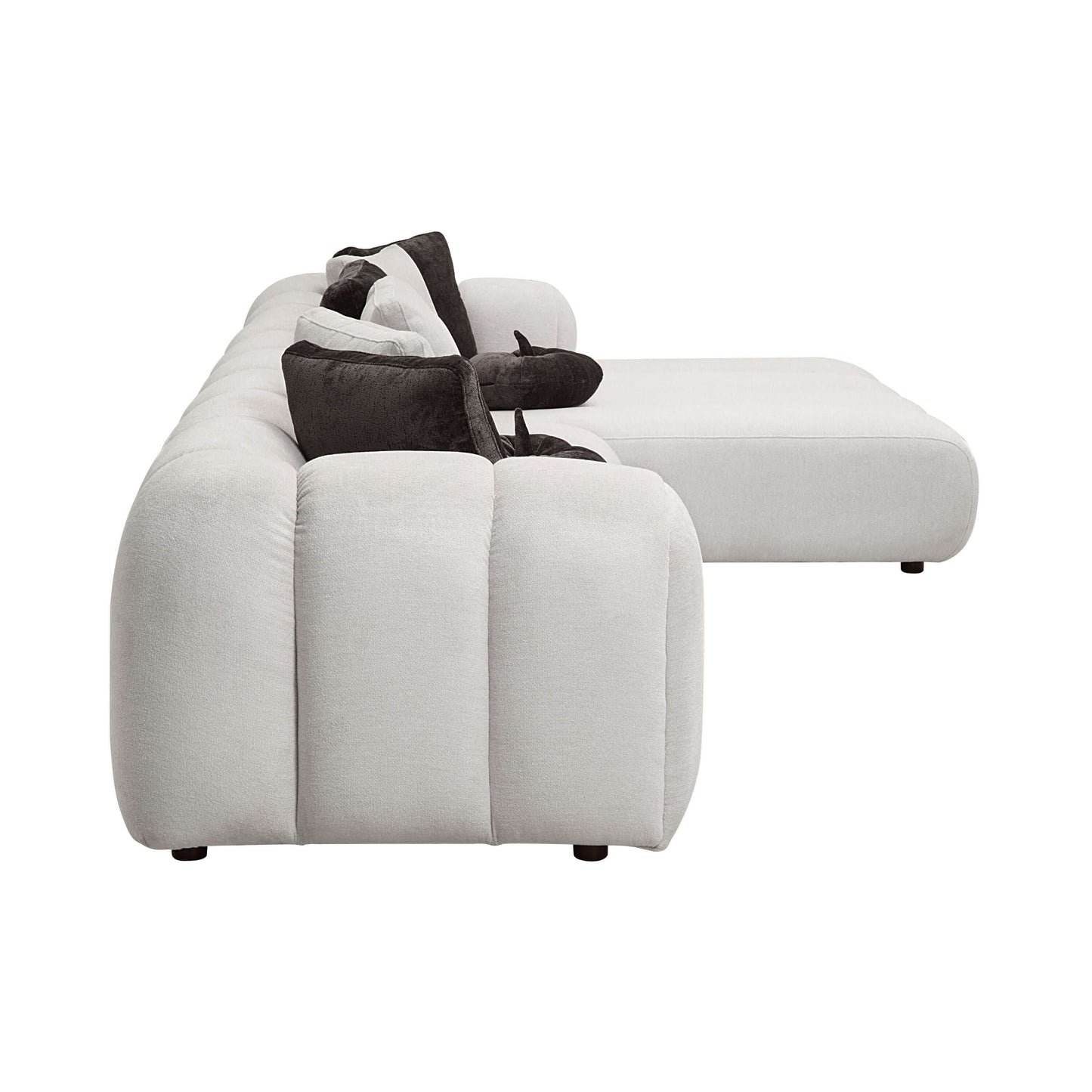White sectional sofa featuring a modern design, oversized chaise, and eight plush pillows in a sleek living room setting.